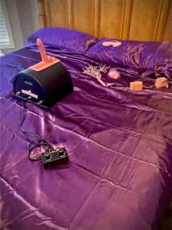 motorbunny sex machine with pink dildo attachment sitting on bed